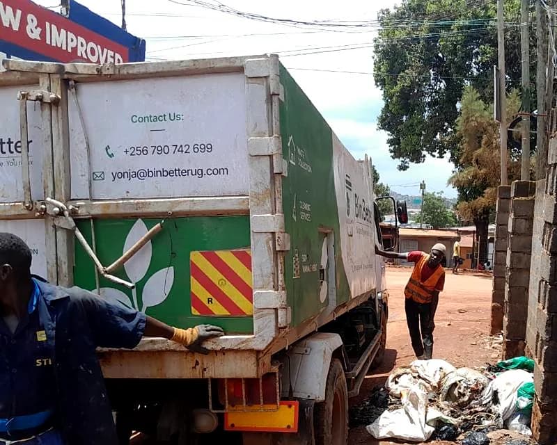 Crew loading waste into the back of a Bin Better truck, the company's telephone and email on the tailgate