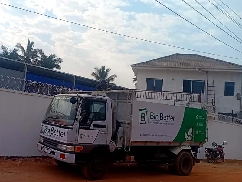 A Bin Better collection truck parked by a white boundary wall